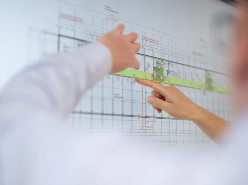 Person zeigt auf einen Architekturplan.