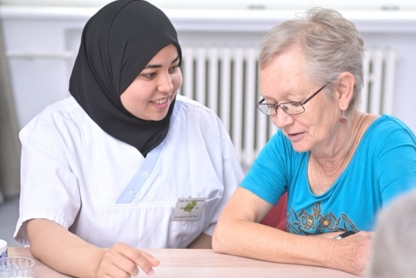 Pfleger*in sitzt an dem Tisch mit einer Bewohner*in und spielt Mensch ärger dich nicht.