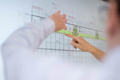 Person zeigt auf einen Architekturplan.