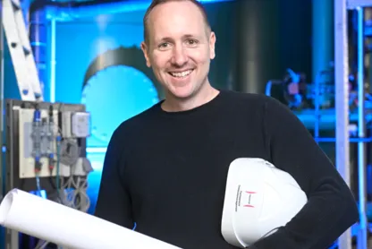 Ingenieur mit Plan in der Hand und Helm unter dem Arm.